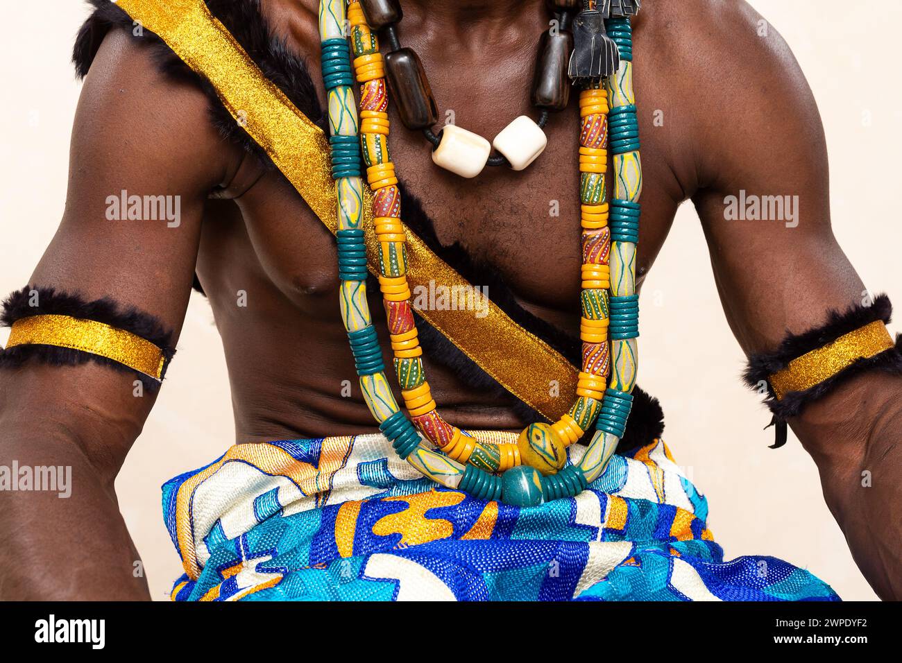 Foto dettagliata di un uomo in tradizionale abbigliamento africano, con elaborati gioielli fatti a mano, una fascia dorata e braccialetti in pelliccia, che incarnano il vibrante e. Foto Stock