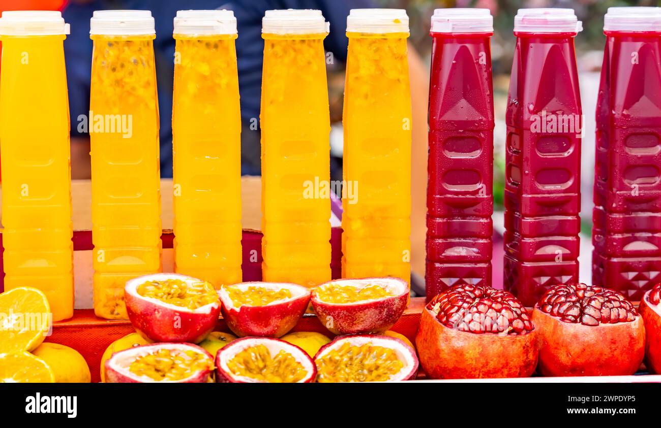 Frutta della passione appena spremuto e succo di melograno in bottiglie per la vendita al bancone Foto Stock