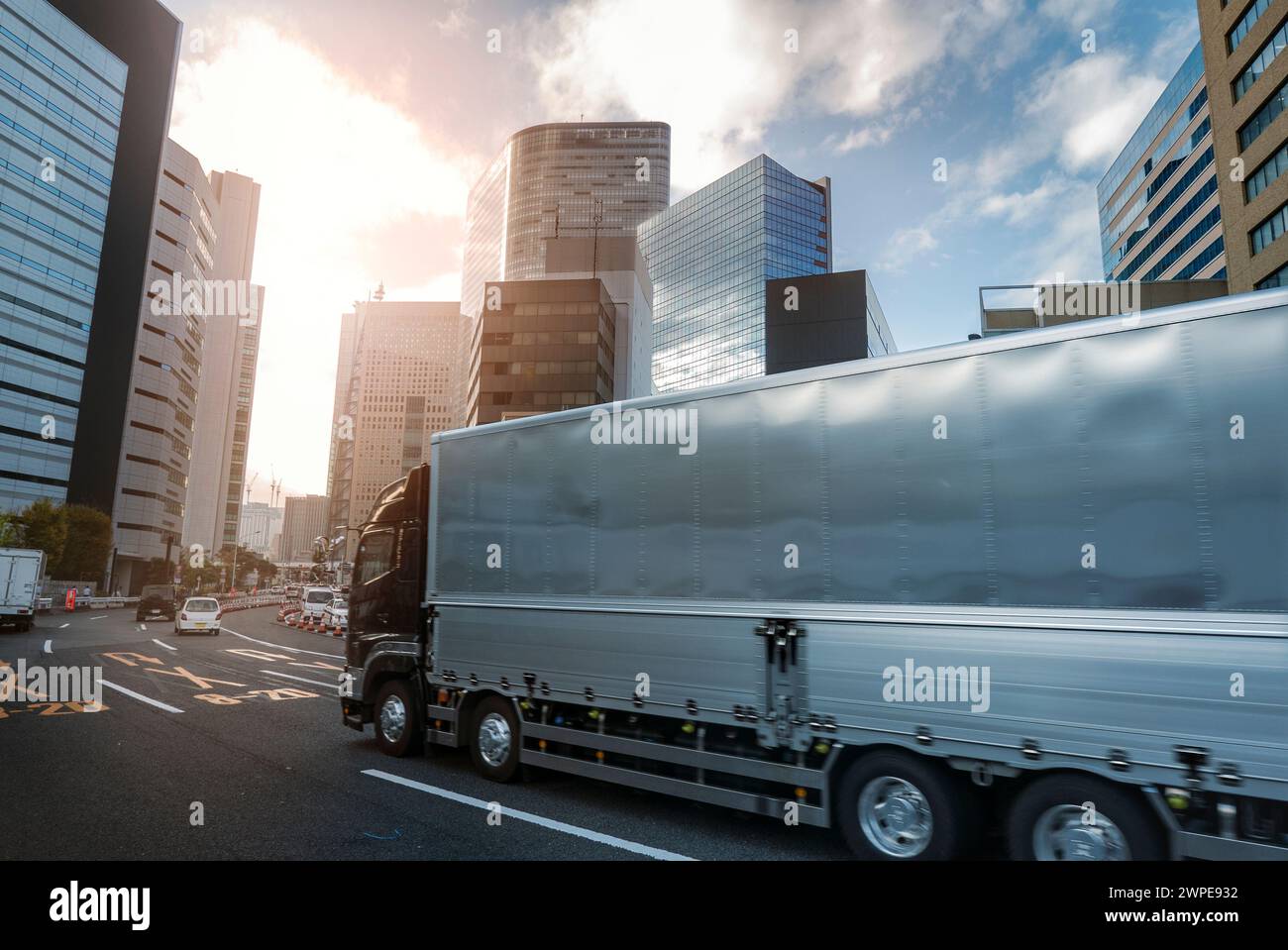 Camion consegna merci con un leggero movimento sfocato che guida attraverso una città moderna tra alti grattacieli Foto Stock