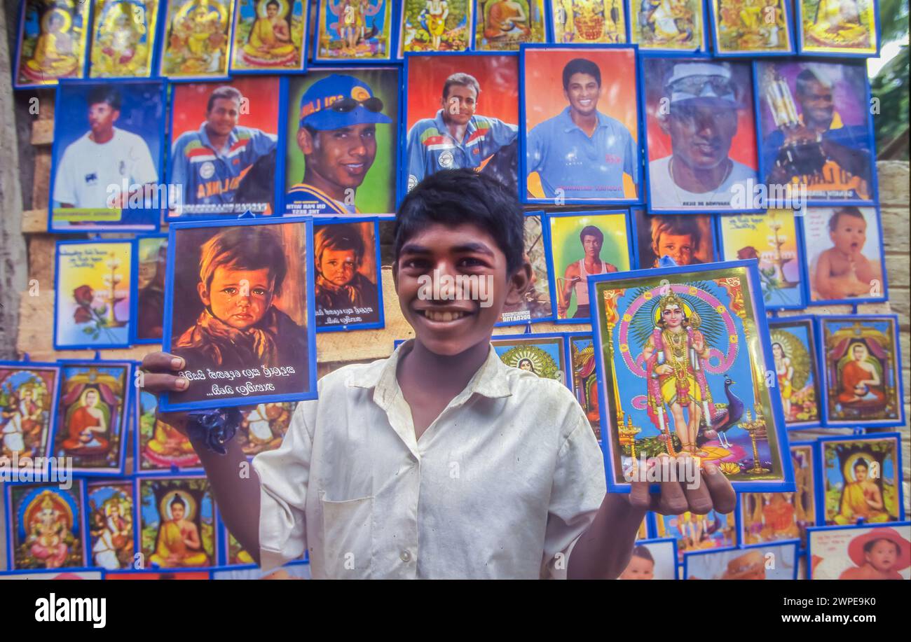 Sri Lanka, Unawatuna, ragazzo vende ritratti di eroi sportivi o di cricket e figure religiose indù e buddiste. Foto Stock