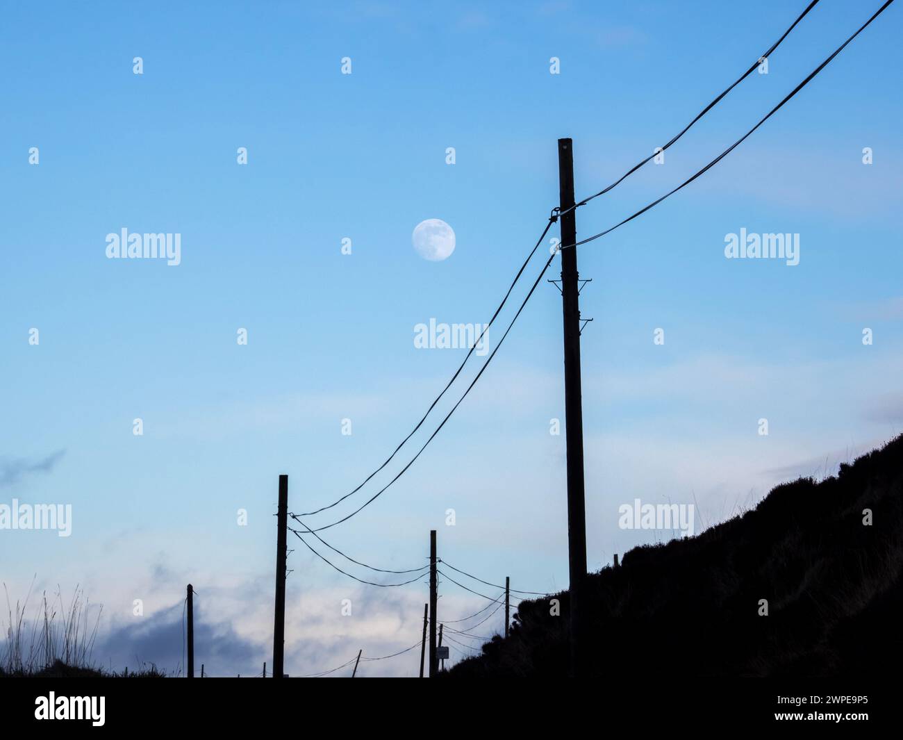 La luna e i pali del telegrafo su Islay, Scozia, Regno Unito. Foto Stock