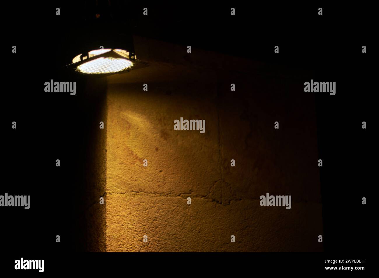 Una luce brillante illumina una parete scura, creando un contrasto drammatico e un'atmosfera misteriosa con spazio per il testo Foto Stock