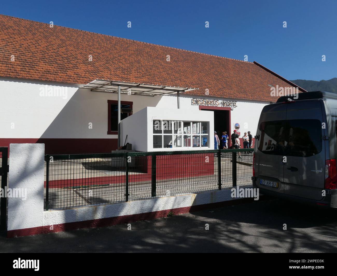 Porto da Cruz, Portogallo. 15 marzo 2023. I turisti si trovano di fronte al tradizionale mulino di canna da zucchero, Companhia dos Engenhos do Norte, a Porto da Cruz, sulla costa settentrionale dell'isola atlantica di Madeira. La canna da zucchero viene trasformata in rum, aguardiente, qui. Lo stabilimento di produzione ospita macchine, alcune delle quali risalgono a oltre 100 anni fa. Credito: Beate Schleep/dpa/Alamy Live News Foto Stock