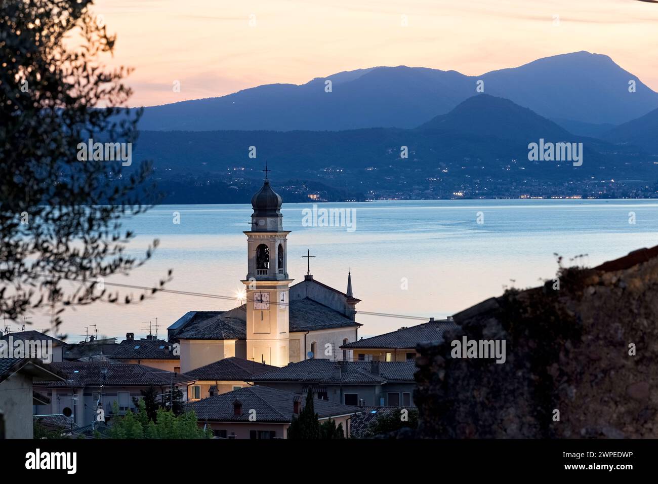 Il paese di Torri del Benaco con la chiesa di San Pietro e Paolo. Sullo sfondo del Lago di Garda. Veneto, Italia. Foto Stock