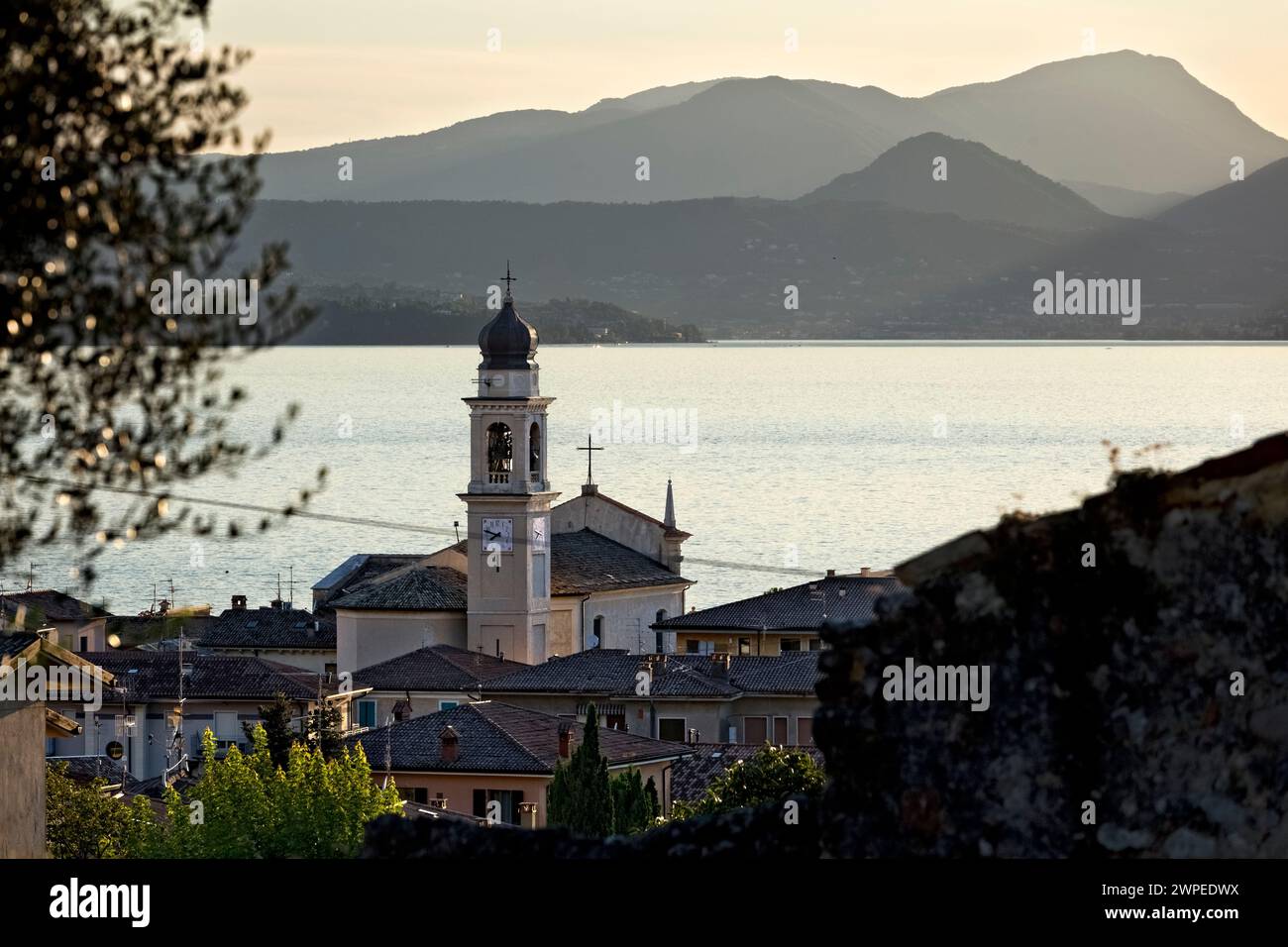 Il paese di Torri del Benaco con la chiesa di San Pietro e Paolo. Sullo sfondo del Lago di Garda. Veneto, Italia. Foto Stock