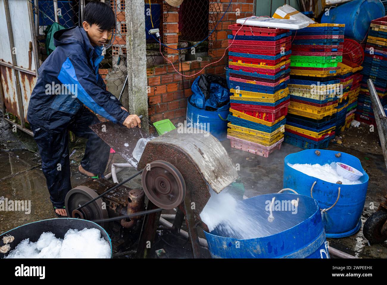 Lavoratore con blocchi di ghiaccio al mercato del pesce di Hoi An Foto Stock