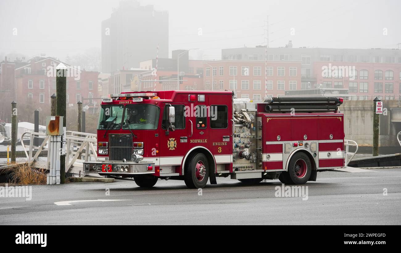 NORWALK, Connecticut, Stati Uniti - 6 MARZO 2024: Parcheggio per camion dei vigili del fuoco rosso vicino al fiume Norwalk, vicino al centro cittadino al Veterans Park nella giornata della nebbia Foto Stock