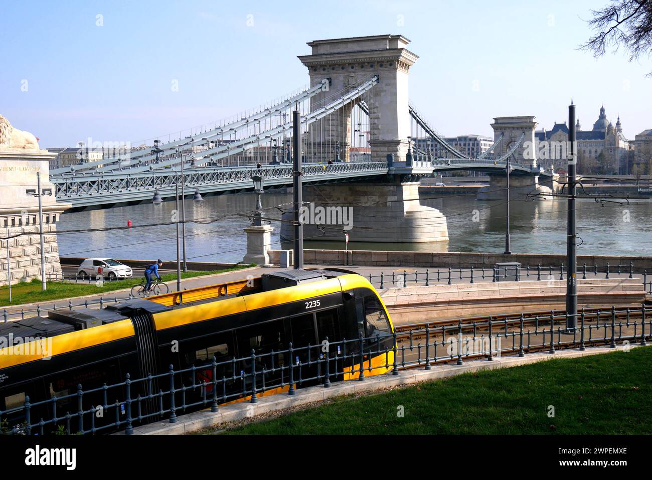 Un tram in primo piano con il Lanchide (Ponte delle catene) che attraversa il Danubio alle spalle, Budapest, Ungheria Foto Stock