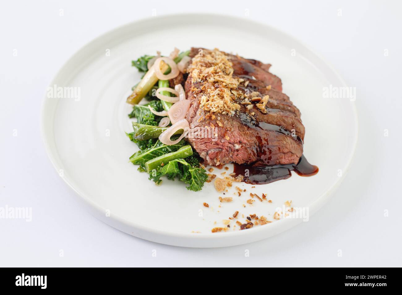Il Sous vide ramoscello di agnello, cotto teneramente, accompagnato da fagioli stagionati, presentato su un piatto bianco incontaminato Foto Stock