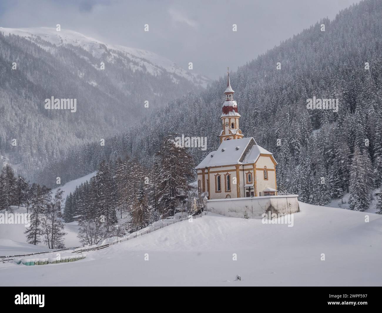 Questa immagine invernale è della chiesa di San Nicola situata nel villaggio di Obernberg, in cima alla valle di Obernbergtal, nel Tirolo austriaco Foto Stock