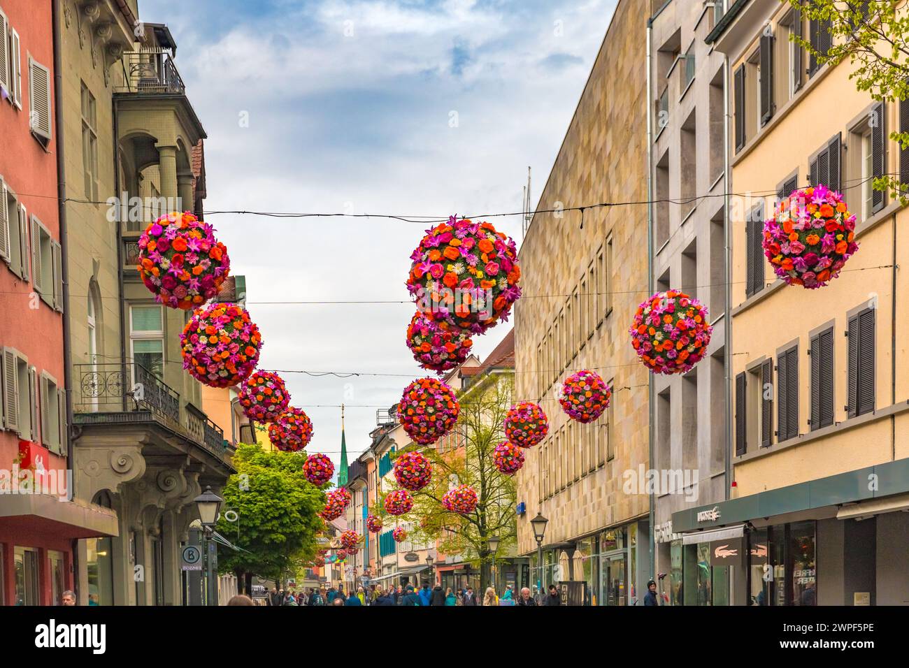 Splendida vista ravvicinata delle colorate palle di fiori appese sulla via dello shopping Hussenstraße nella città vecchia di Costanza (Costanza) sul lago... Foto Stock