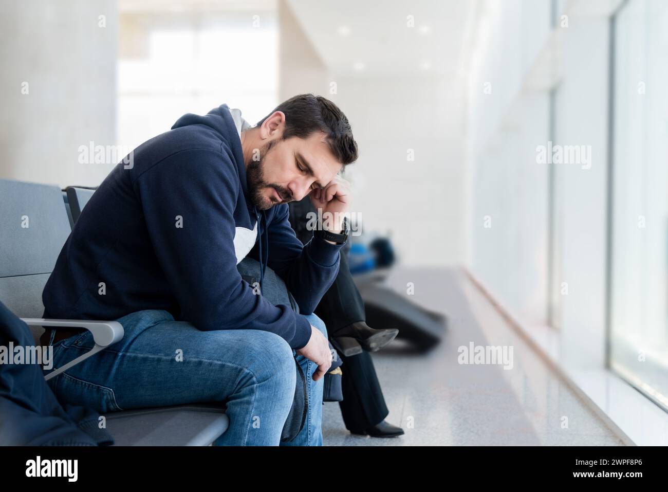 Uomo di mezza età che dorme in una sala d'attesa. Stanco di aspettare il treno, l'aereo, il dottore Foto Stock