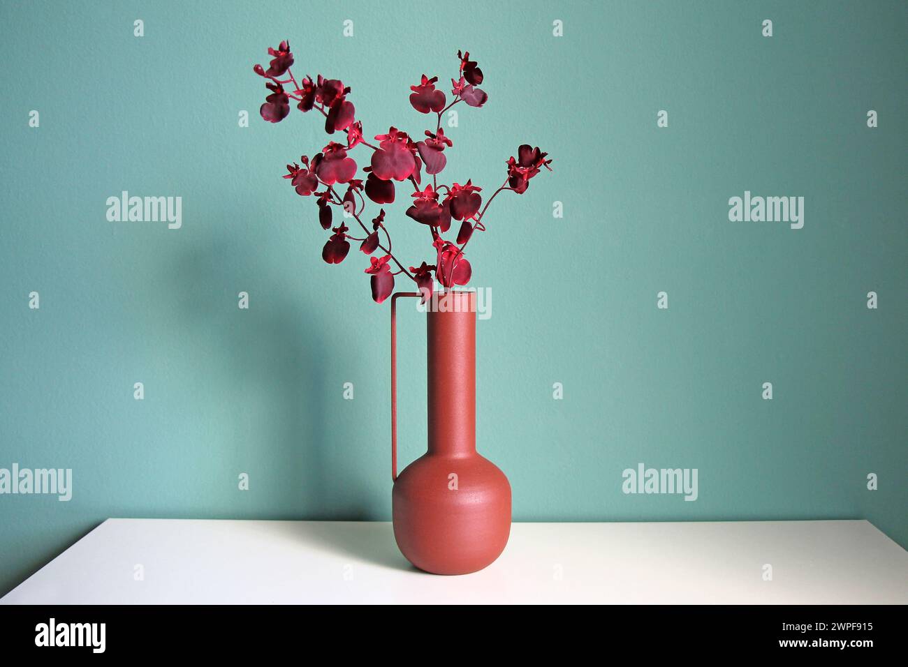Ramo fiorito in un moderno vaso in ceramica su un tavolo bianco. Stile orientale desiderato. Spazio per il testo. Foto Stock