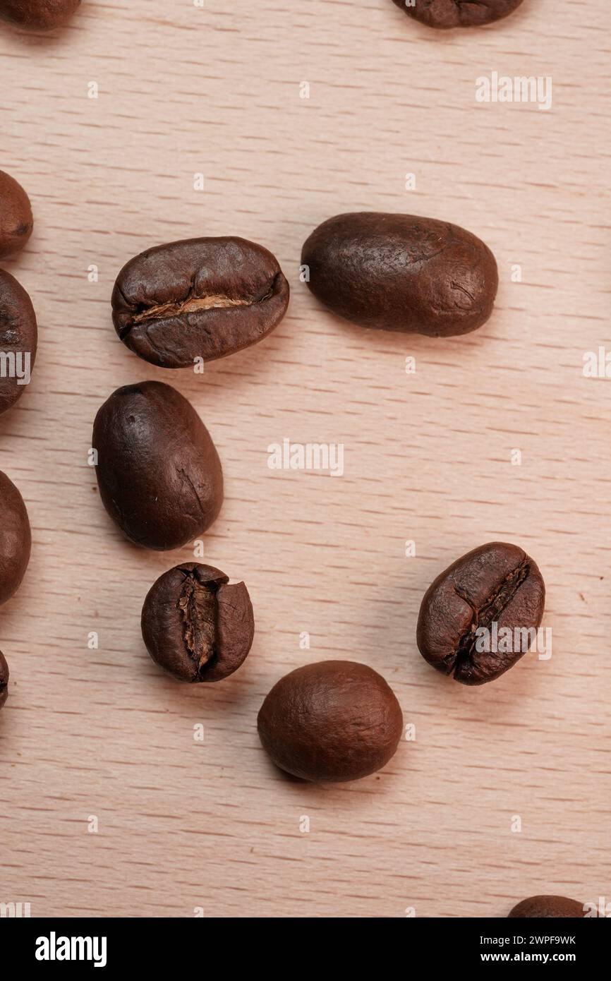 Creazioni con caffeina. La lettera C sta per caffè. Arte di fagioli crudi su una superficie in legno. Foto Stock