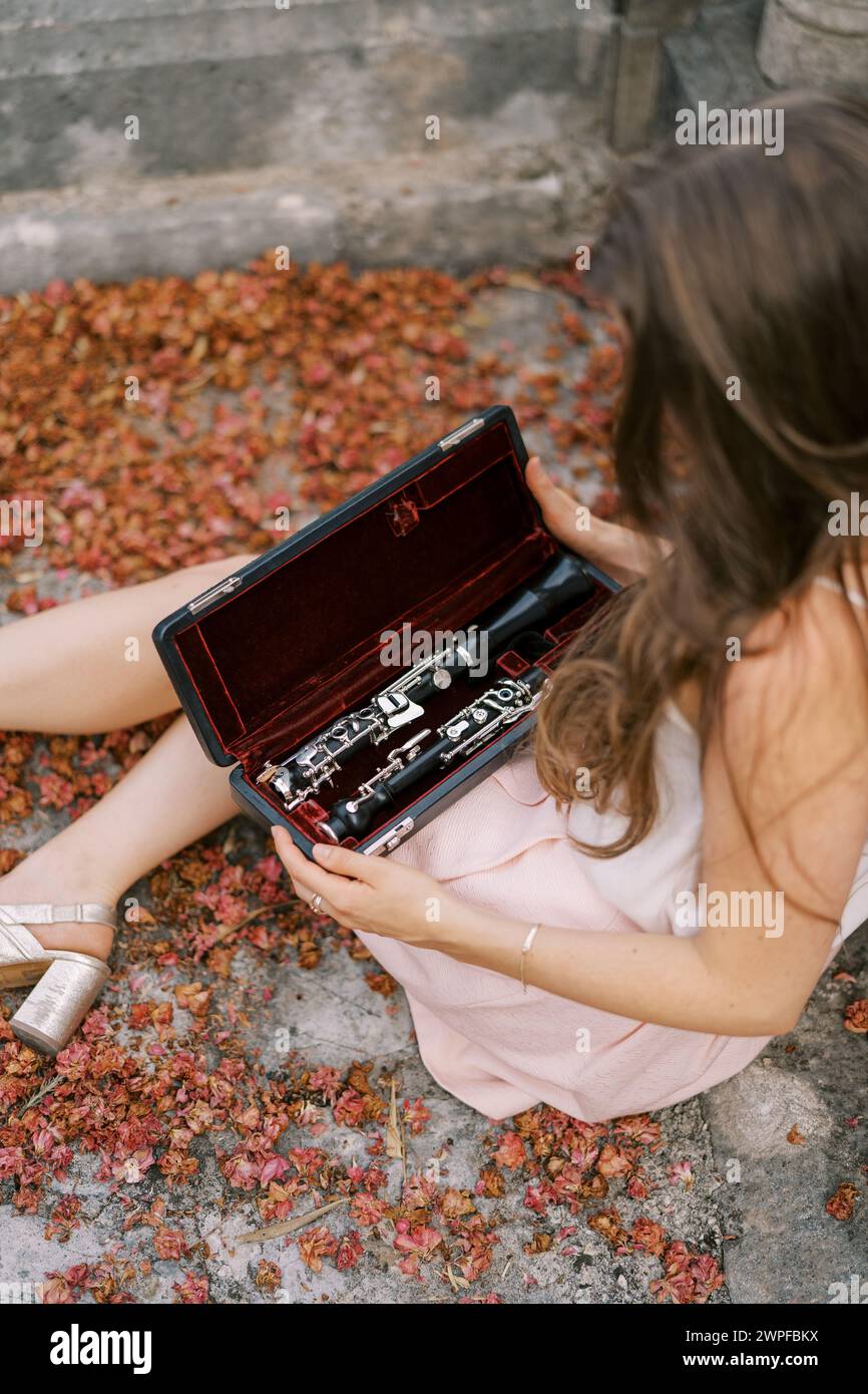 La musicista si siede sulla terrazza di un'antica villa con una cassa di clarinetto aperta in ginocchio Foto Stock