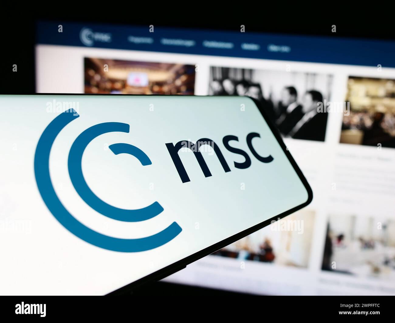 Cellulare con logo dell'evento annuale Munich Security Conference (MSC) davanti al sito web. Mettere a fuoco il display del telefono. Foto Stock