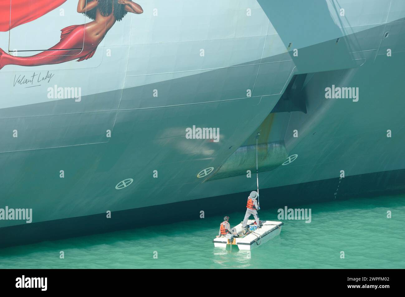 Porto delle navi da crociera di St Johns, Antigua - 1 febbraio 2024: Lavoratori che dipingono lo scafo della nave Foto Stock