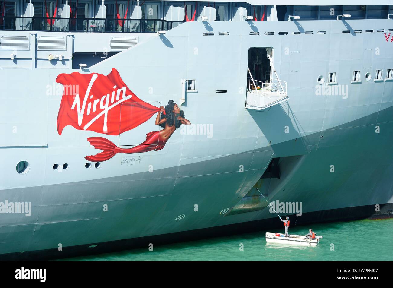 Porto delle navi da crociera di St Johns, Antigua - 1 febbraio 2024: Lavoratori che dipingono lo scafo della nave Foto Stock