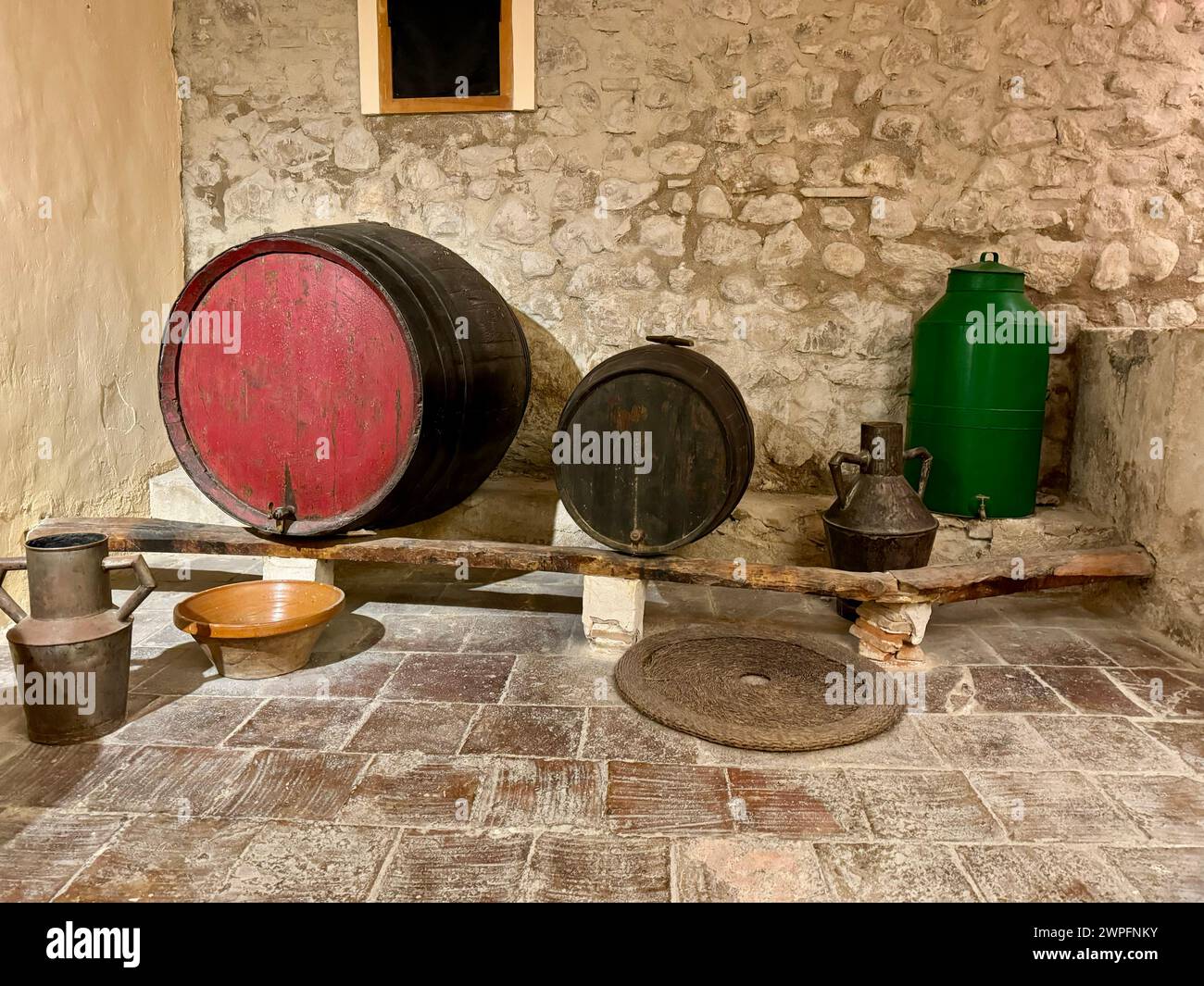Un'antica cantina di vini in una tipica casa di campagna spagnola. C'è una grande botte di legno e alcuni utensili e utensili per fare il vino. Foto Stock
