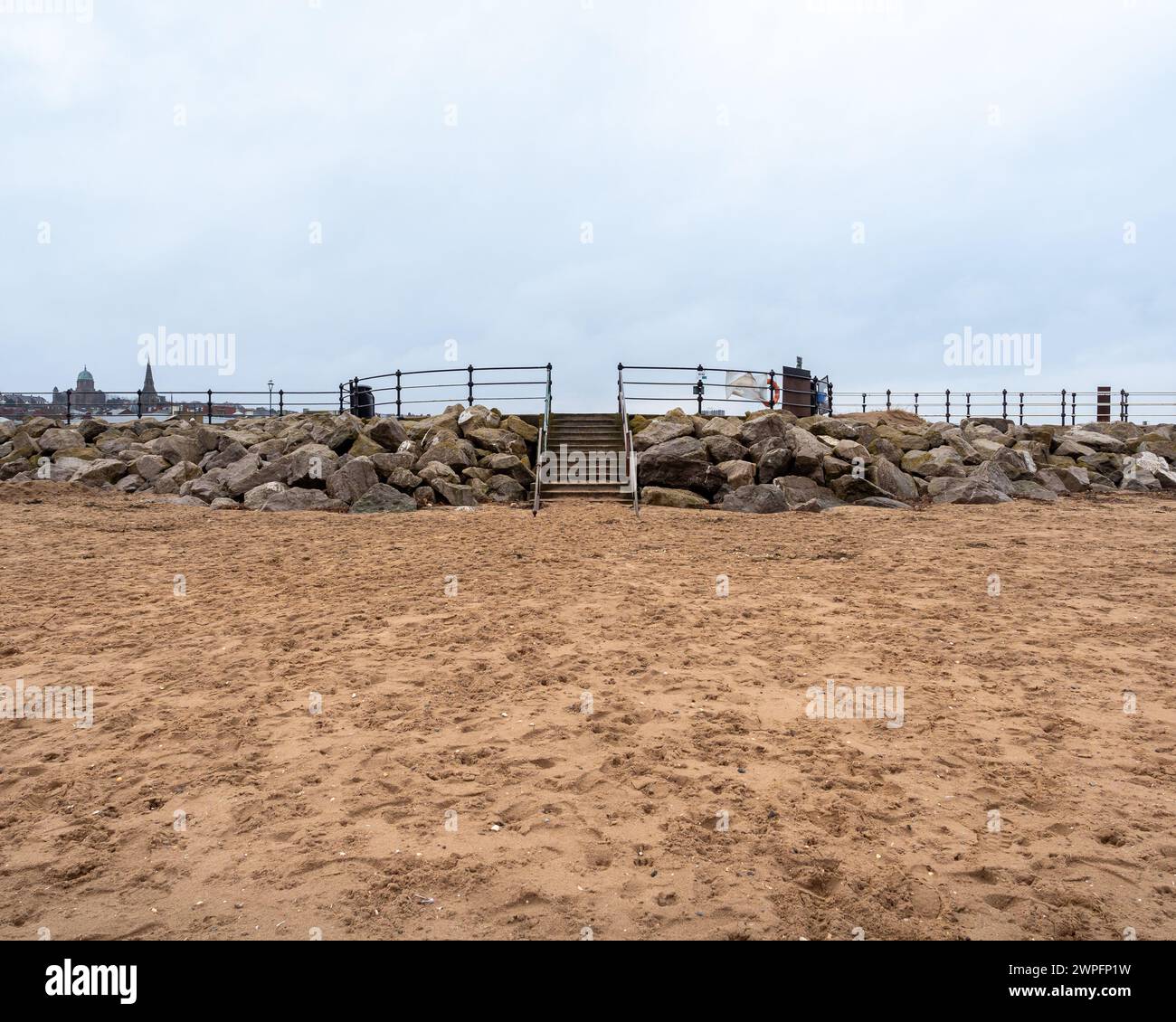 Scalini di pietra fuori dalla spiaggia di sabbia vuota fino alle pareti del mare fino al lungomare, giorno dell'inverno. Foto Stock