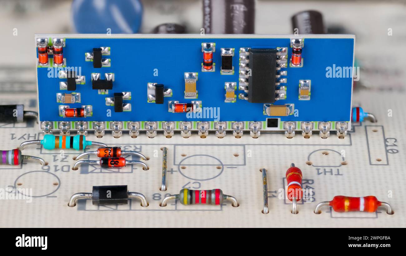 Circuito integrato e componenti elettronici a montaggio superficiale su un circuito stampato blu. Primo piano di un modulo ibrido su una scheda di cablaggio stampata bianca. Controllo automatico. Foto Stock