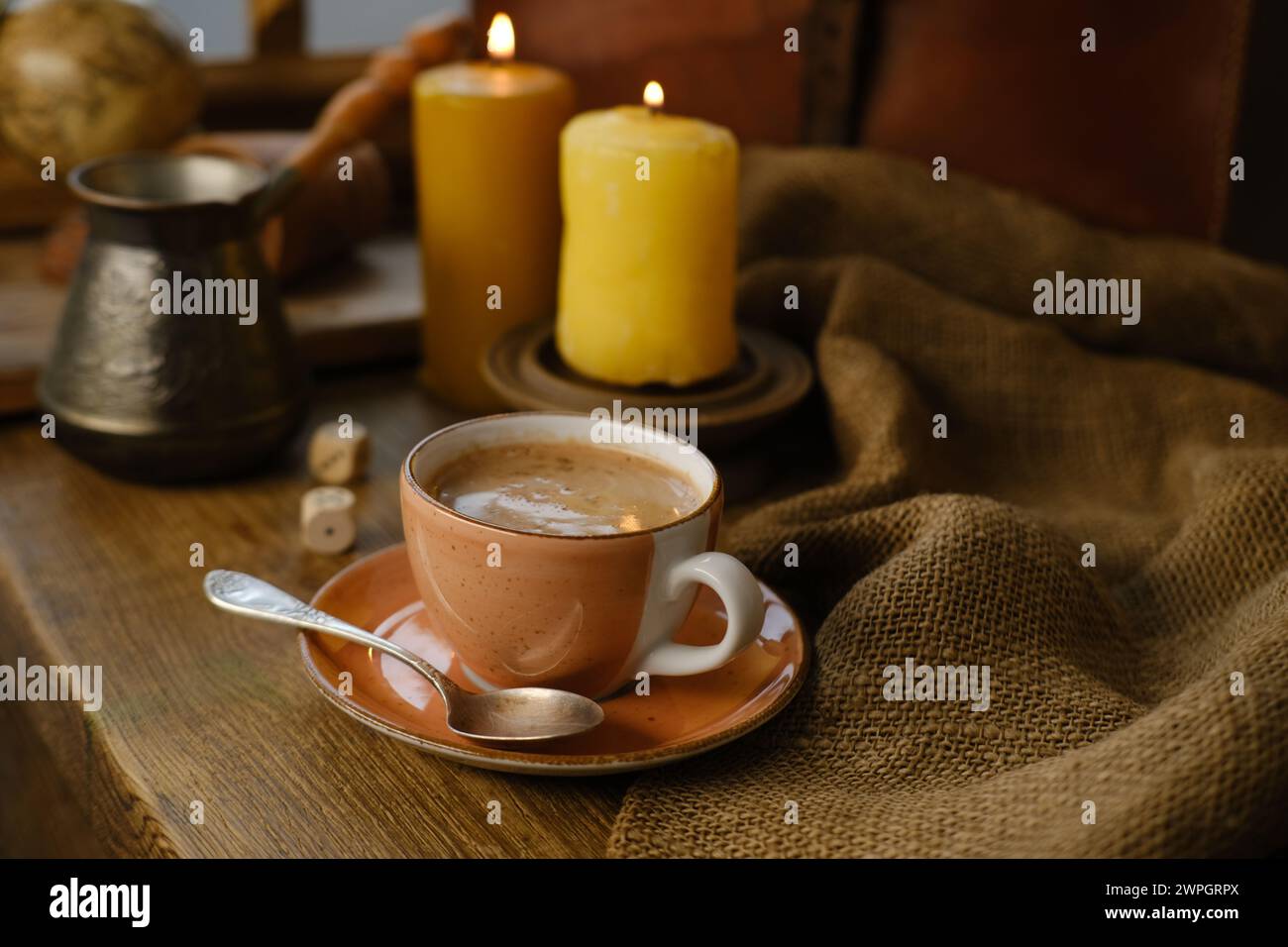 tazza con caffè da bere su un vecchio tavolo in legno vintage, caffettiera in metallo, candele bruciate, caffeina migliora il funzionamento del cervello umano, stimola il nervosismo Foto Stock