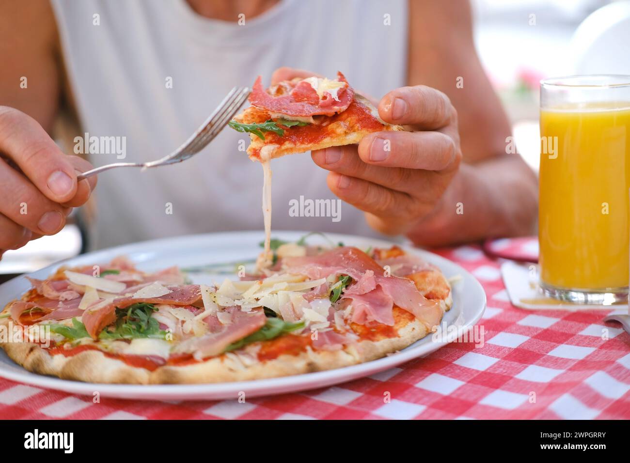 L'uomo mangia la pizza italiana, con salame, formaggio, rucola, le mani maschili prendono pezzi di pizza con salame, formaggio, rucola, mani con il cibo da vicino, schiacciano Foto Stock