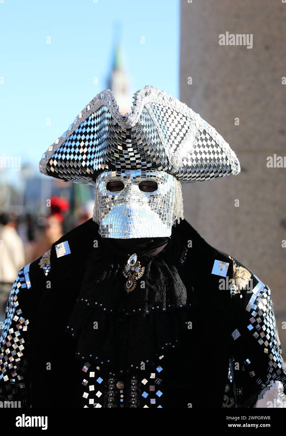 Venezia, VE, Italia - 13 febbraio 2024: Uomo mascherato che indossa un costume originale in tessuto pregiato e specchi che riflettono la luce al Carnevale di Venezia Foto Stock