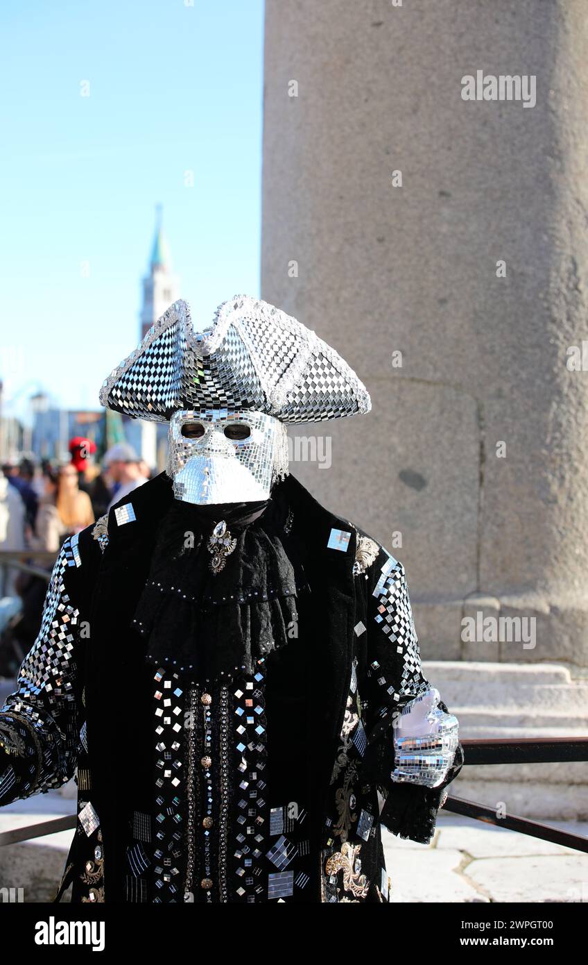 Venezia, VE, Italia - 13 febbraio 2024: Uomo mascherato che indossa un costume originale realizzato in tessuto pregiato e molti specchi che riflettono la luce al Venice Carn Foto Stock