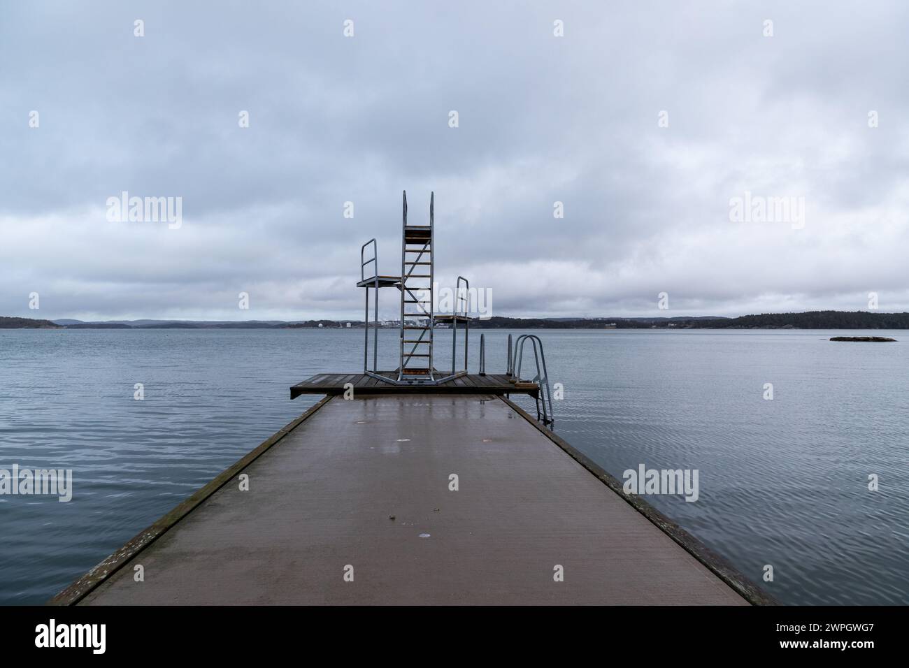Ponte e torre per immersioni circondati da acque calme in giornata grigia Foto Stock