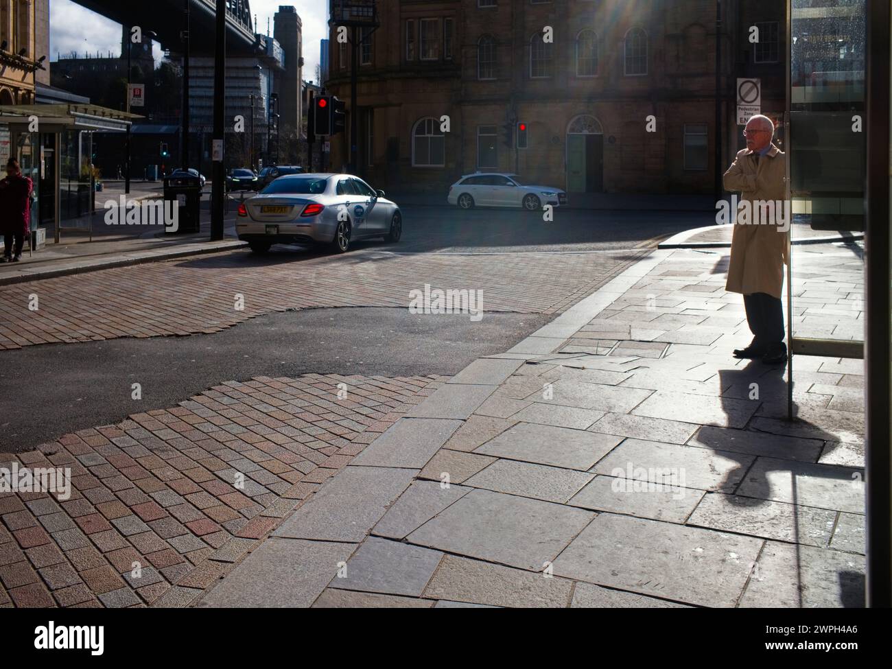 Uomo che indossa un mac con la mano che entra nella tasca interna con un bagliore sull'obiettivo Foto Stock