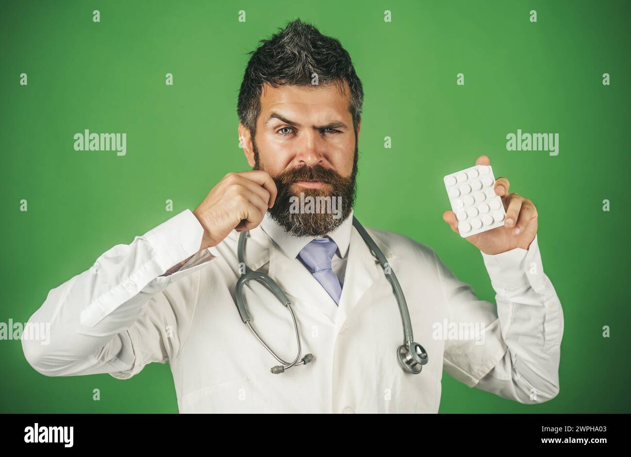 Medico professionista maschile con pillole in blister. Concetto di prescrizione di farmaci farmaceutici. Medico barbuto in abito medico bianco con Foto Stock
