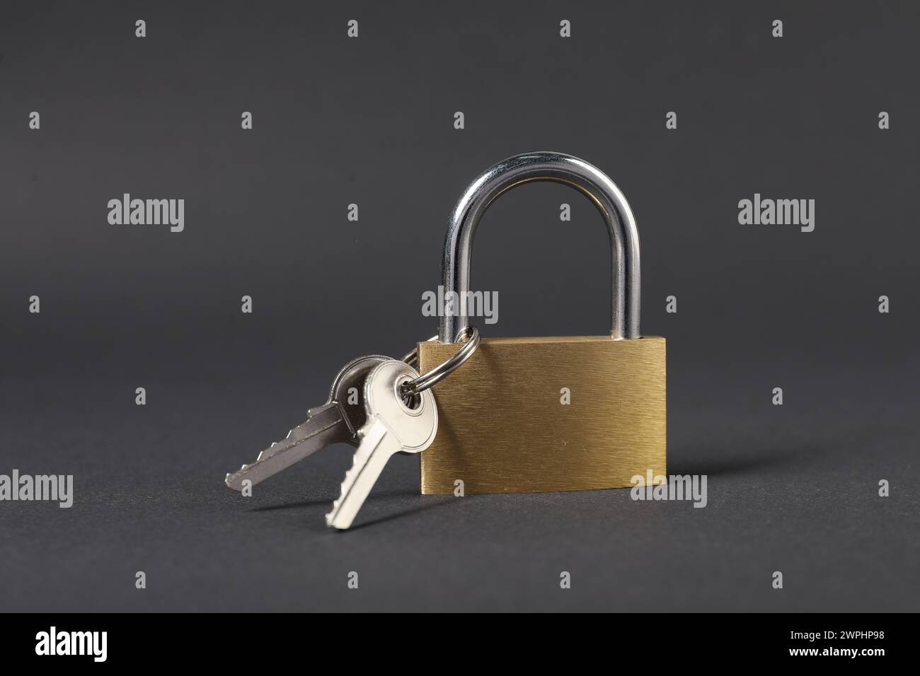 Lucchetto in acciaio con chiavi su sfondo grigio scuro, primo piano Foto Stock