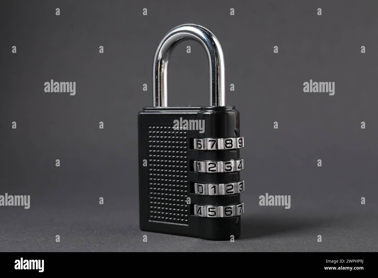 Un lucchetto a combinazione in acciaio su sfondo grigio scuro, primo piano Foto Stock