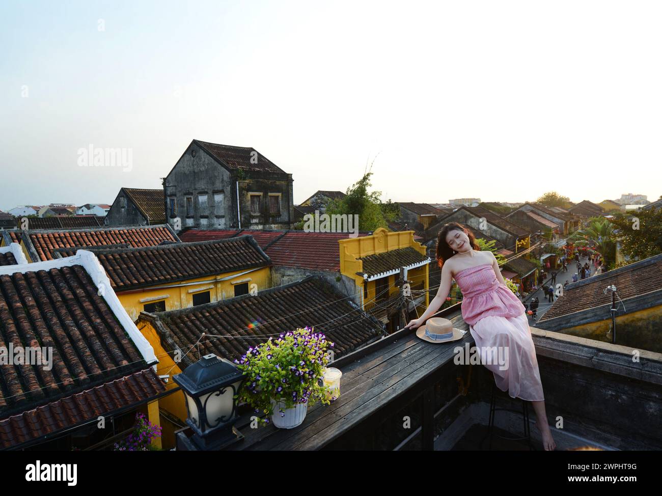 Una donna asiatica che posa per uno scatto con i tetti tradizionali nella città vecchia di Hoi An in Vietnam. Foto Stock
