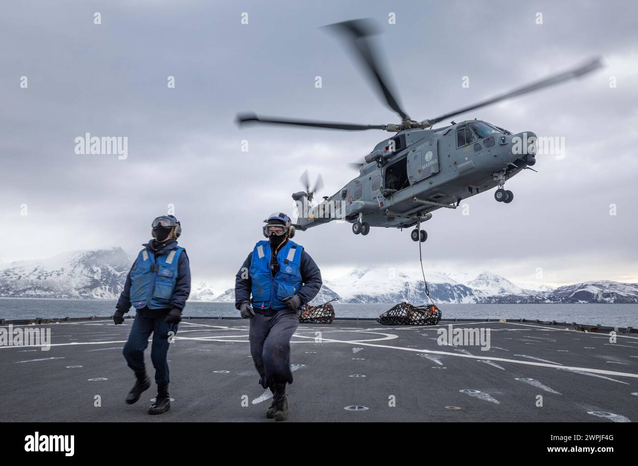 Seaman Caleb Degabriele e Boatswain's Mate di 3a Classe Ali Khadour ritornano da carico agganciato a un elicottero della Marina italiana Foto Stock
