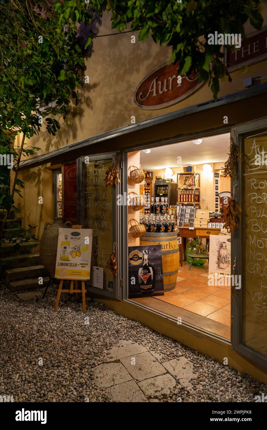 10.15.2023 - Rovigno, Croazia: Negozio di liquori aura a Rovigno di notte con un'atmosfera calda e accogliente . Foto Stock