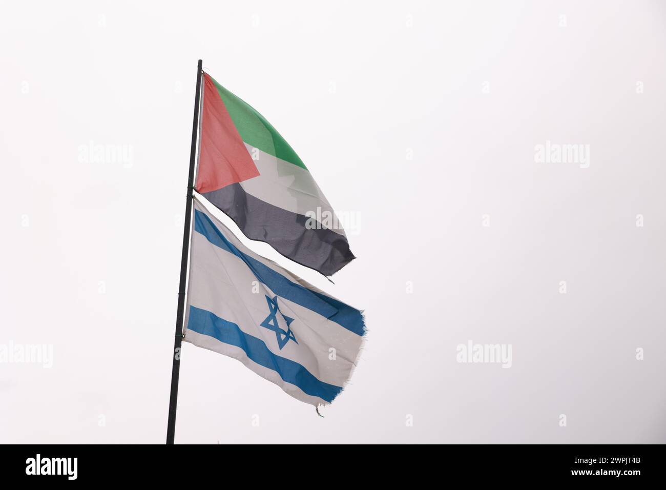 Una bandiera con una stella bianca e strisce blu sta sventolando accanto a un'altra bandiera. Le due bandiere sono di colori e dimensioni diversi Foto Stock