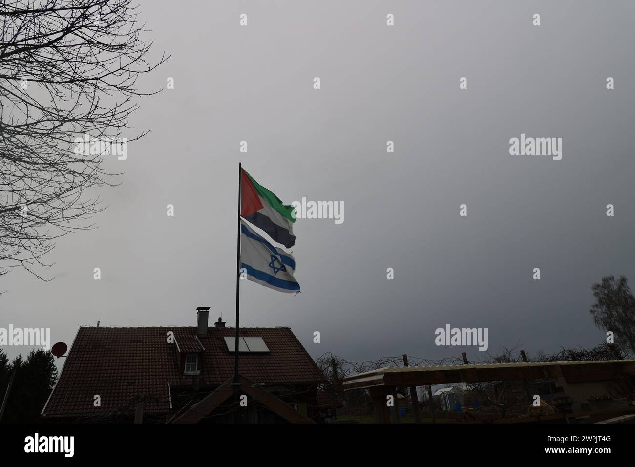 Una bandiera con sopra la parola Israele sta sventolando in aria. Il cielo è nuvoloso e la casa è sullo sfondo Foto Stock
