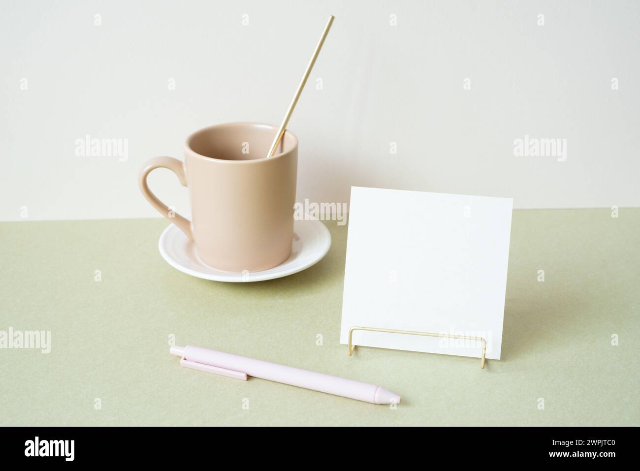 Blocco note vuoto con supporto, penna e tazza sulla scrivania. sfondo bianco avorio. cancelleria per ufficio Foto Stock