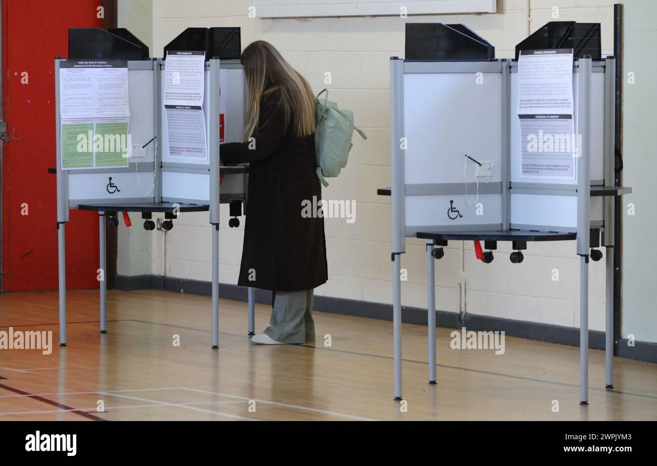 Voto in corso presso la Old St Josephs Gym Hall di Dublino, mentre l'Irlanda tiene referendum sulle modifiche proposte al testo della Costituzione relative alle aree di famiglia e cura. L'emendamento sulla famiglia propone di estendere il significato di famiglia al di là di quello definito dal matrimonio e di includere quelli basati su relazioni "durature”. L'emendamento Care propone di eliminare i riferimenti ai ruoli e ai doveri di una donna in casa e di sostituirlo con un nuovo articolo che riconosce gli assistenti familiari. Data foto: Venerdì 8 marzo 2024. Foto Stock