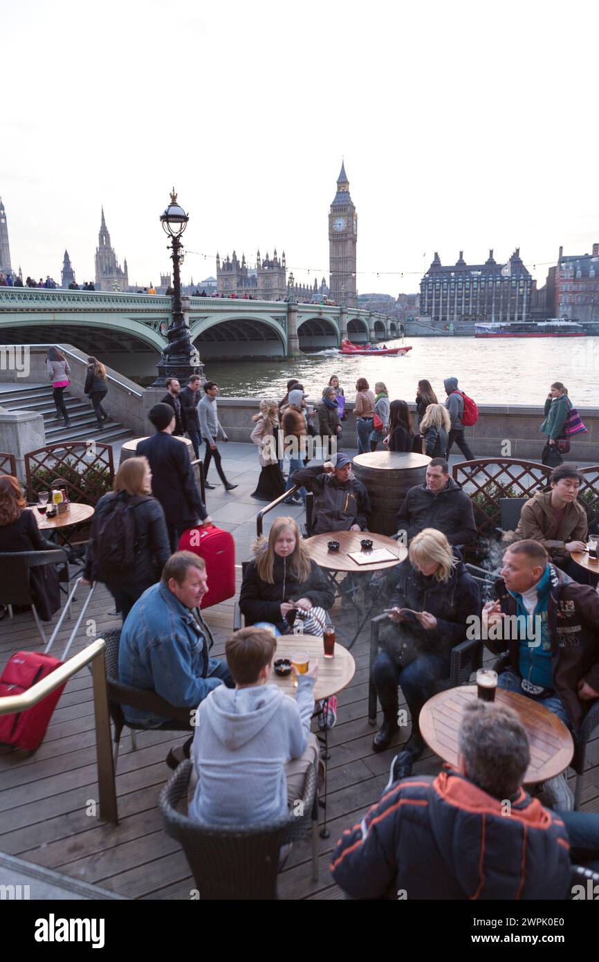 Regno Unito, Londra, persone che si godono un drink al County Hall Arms con Westminster sullo sfondo. Foto Stock