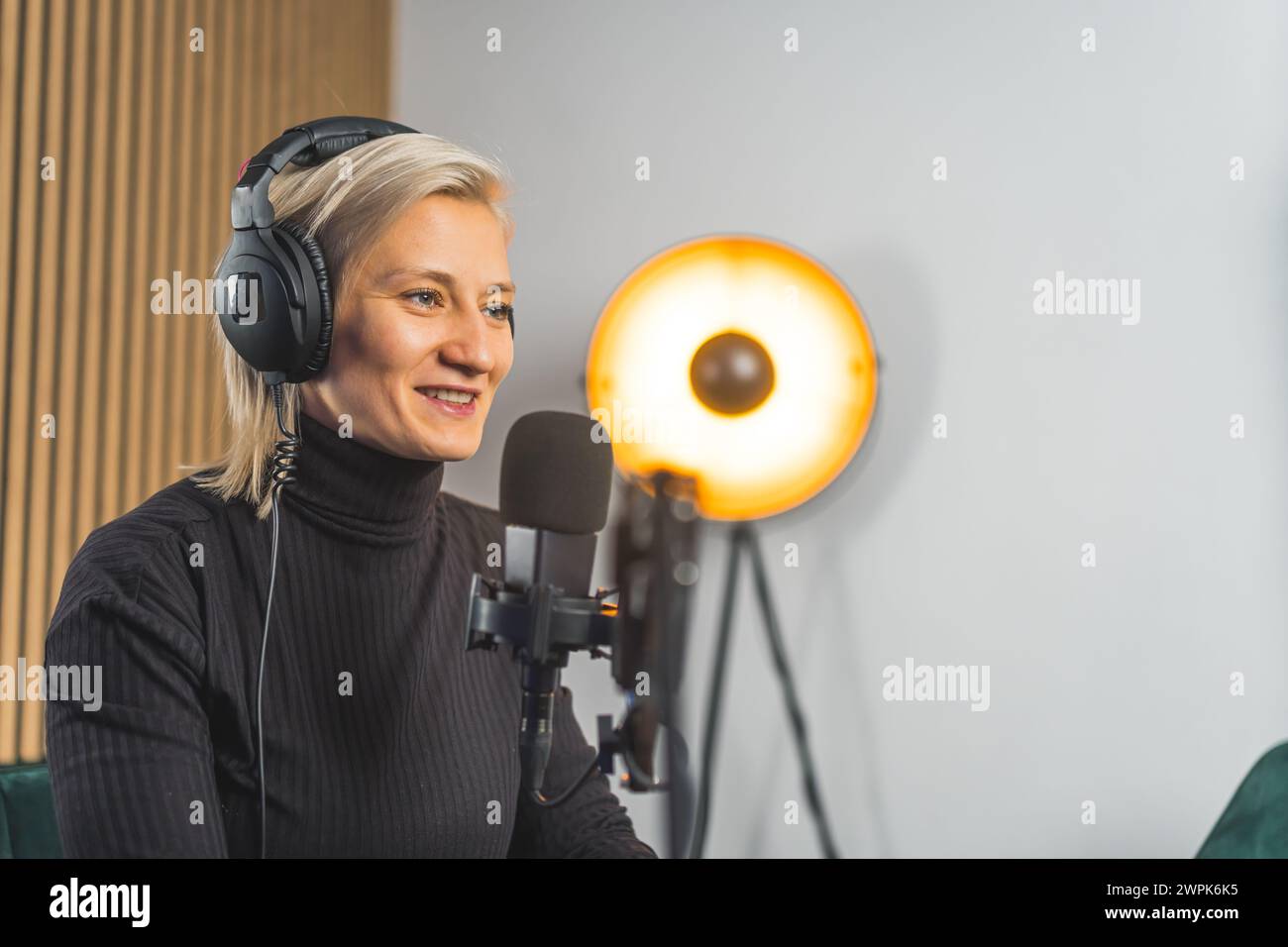 Donna caucasica sorridente, microfono e podcast o presentatore radiofonico che parla per la trasmissione, lo streaming live o il discorso. Foto di alta qualità Foto Stock