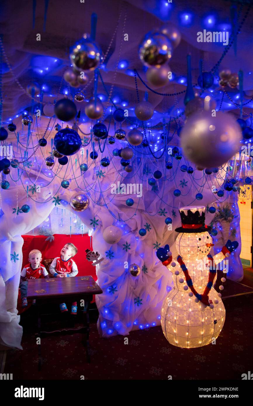 28/11/14 Jacob (2) e Reuben (3) si trovano nell'angolo del pub che è stato trasformato nella grotta di Babbo Natale. Il pub Hanging Gate a Chapel en le Frith, in th Foto Stock