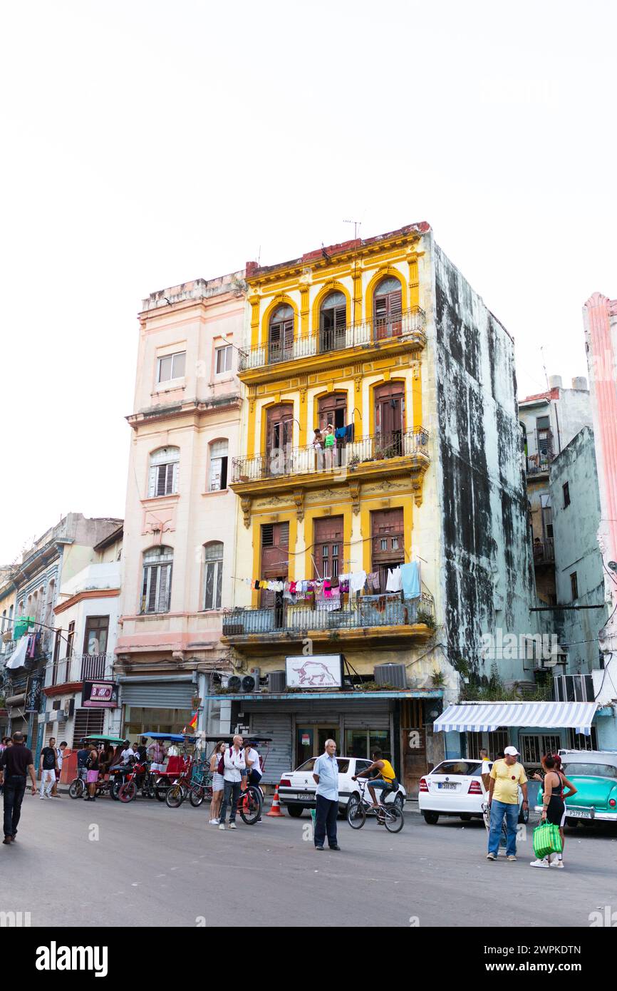 Edificio giallo e rosa a l'Avana con un vivace mercato Foto Stock