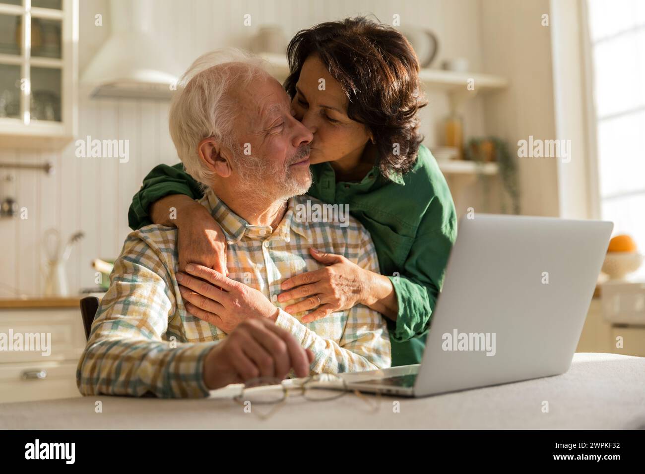 una donna anziana bacia e abbraccia il vecchio marito dai capelli grigi Foto Stock