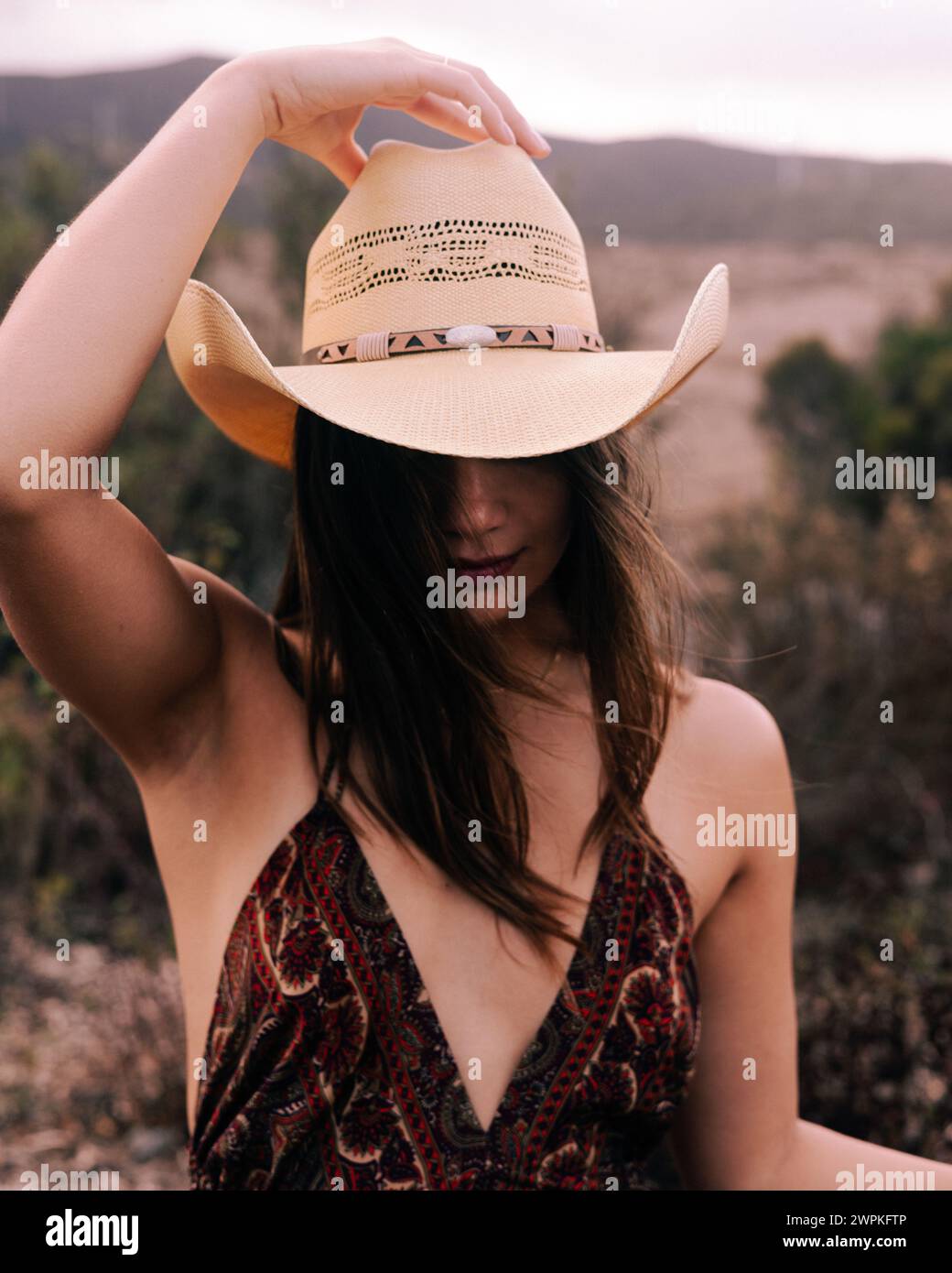 Donna multirazziale che tiene il cappello in cima alla testa fuori pista a San Diego Foto Stock