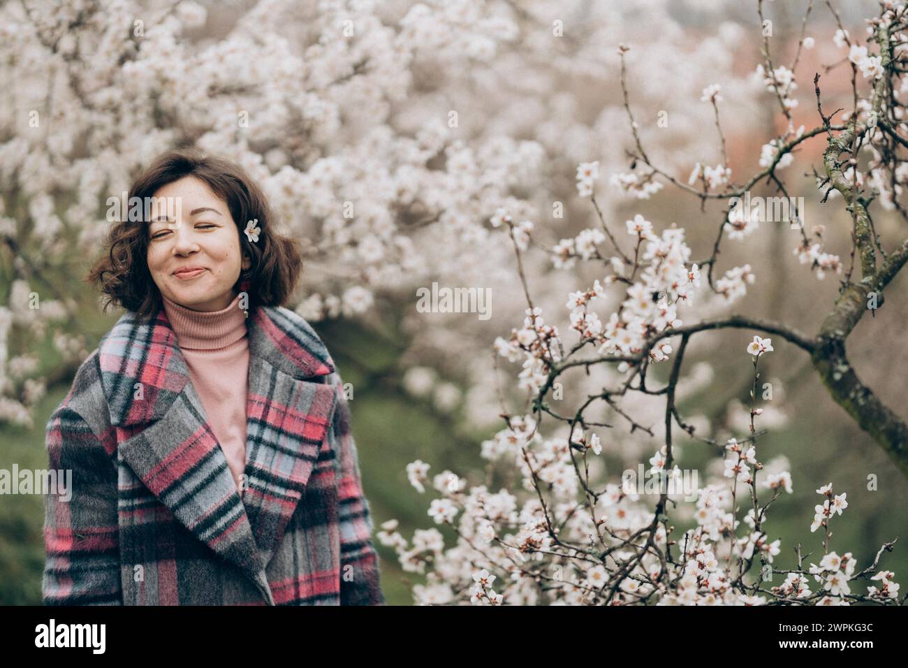 Giovane donna sorridente in un giardino di mandorle in fiore a Praga Foto Stock