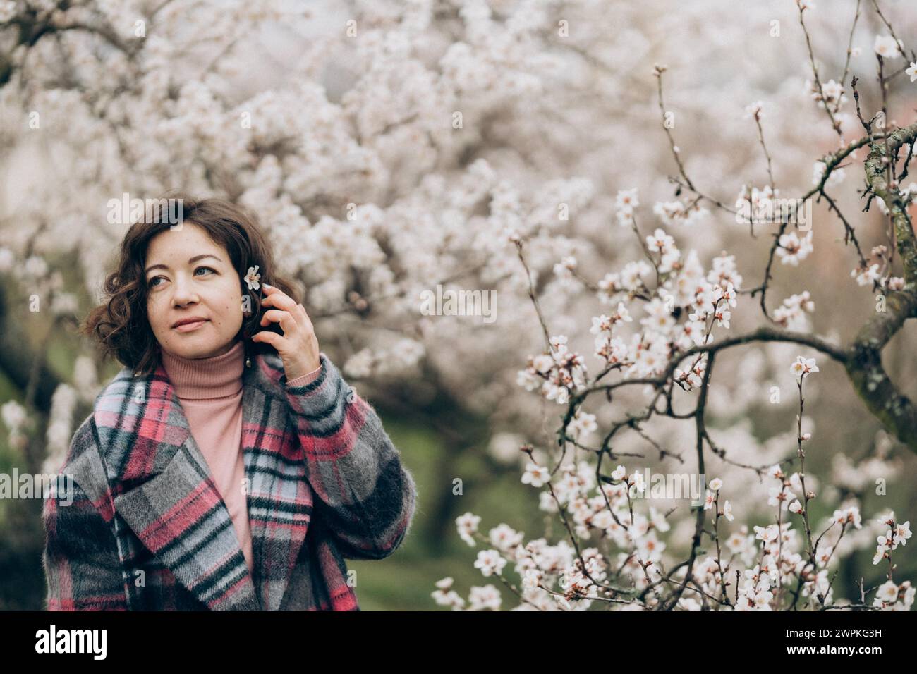 Giovane donna sorridente in un giardino di mandorle in fiore a Praga Foto Stock