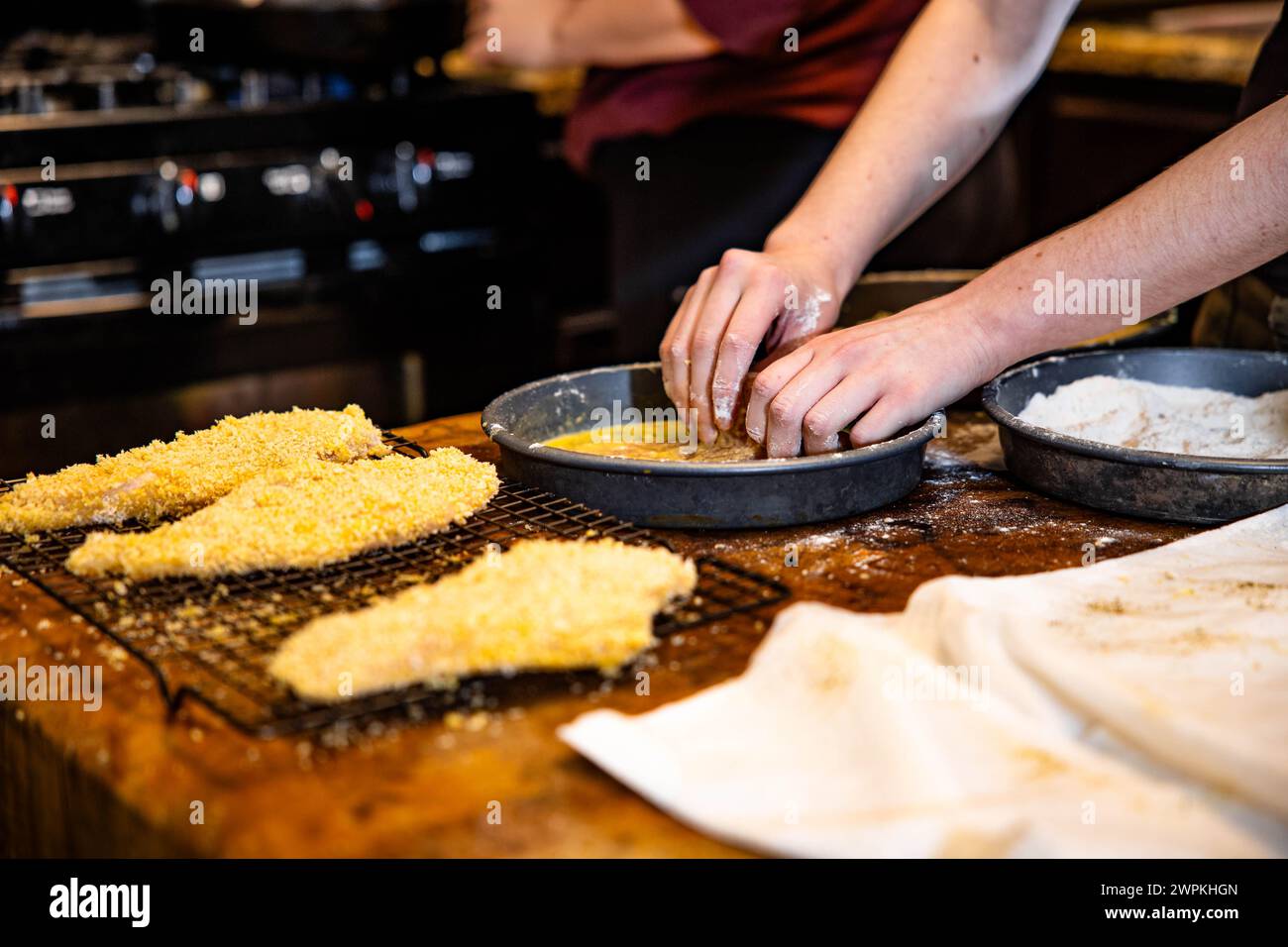 Una persona che prepara il cibo su un tavolo da cucina. Foto Stock